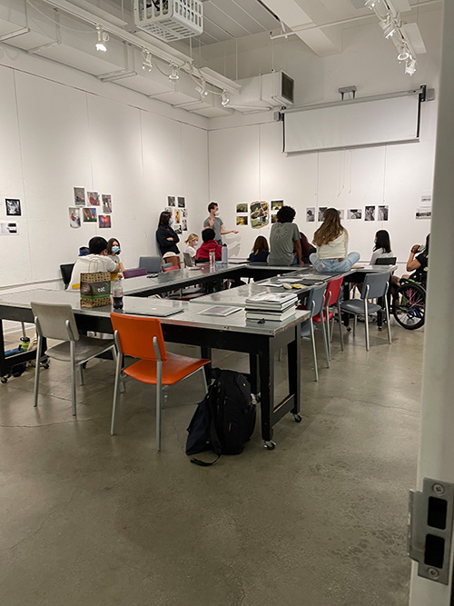 a class discussing photographs pinned to a wall